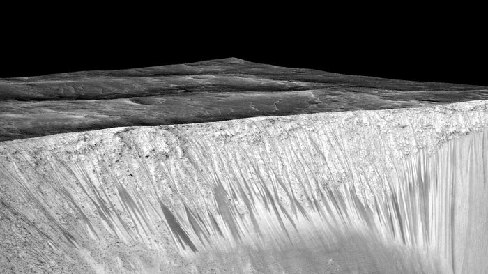 Streaks a few hundred feet in length appear on the walls of Garni crater on Mars. Scientists suspect they are formed by the flow of briny, liquid water on Mars. (NASA/JPL/University of Arizona)