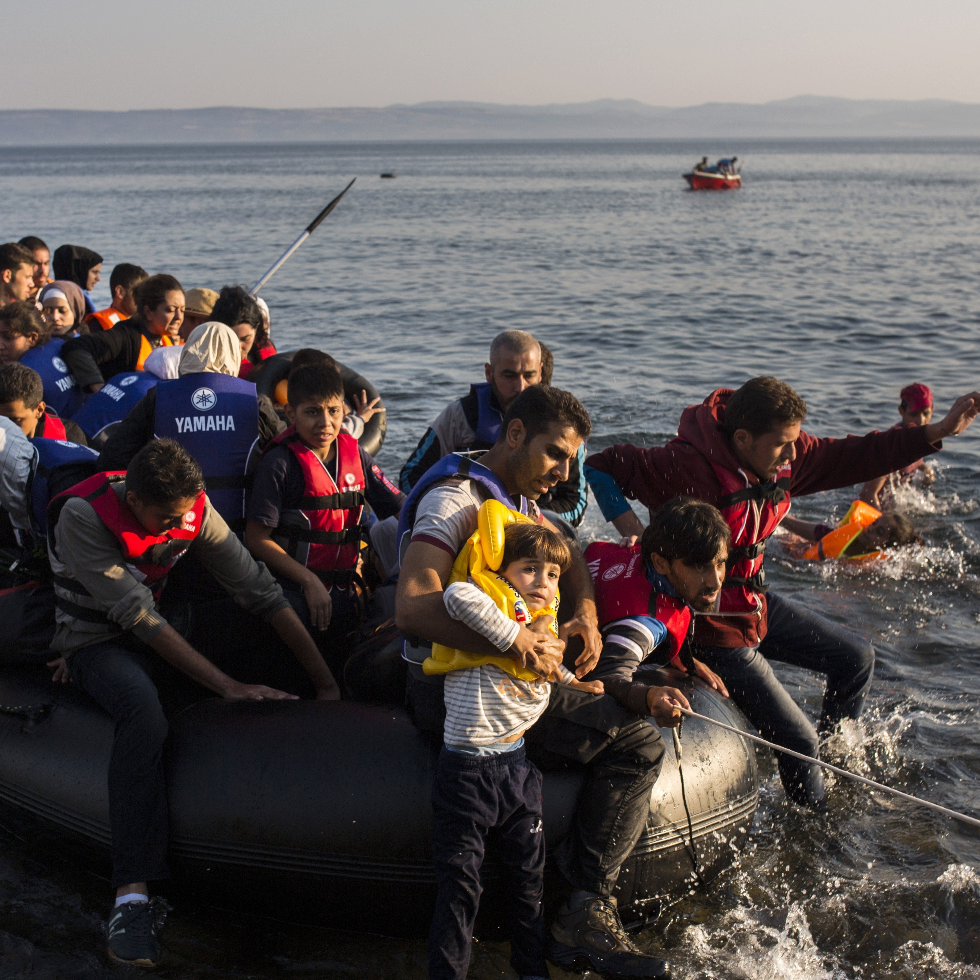 Migrants from Syria and Afghanistan arrive on an overcrowded dinghy from the Turkish coasts to the Greek island of Lesbos, Monday, July 27, 2015.