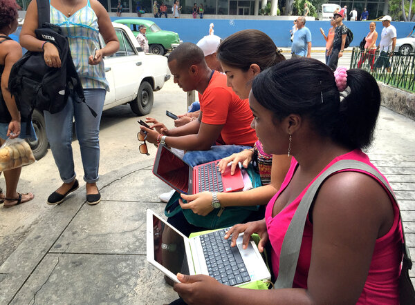 Havana residents huddle in front of the Habana Libre hotel, trying to log onto the Internet. (Carrie Kahn/NPR)