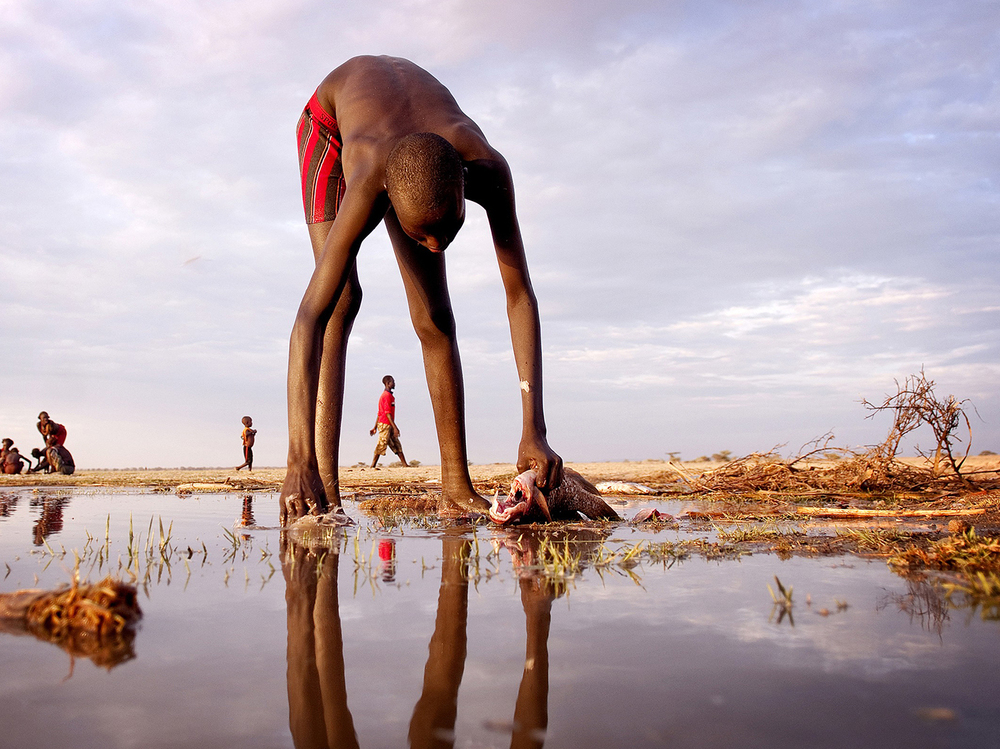 A Daasanach fisherman guts and cleans a fish on the eastern shore of Lake Turkana near the border of Ethiopia and Kenya.