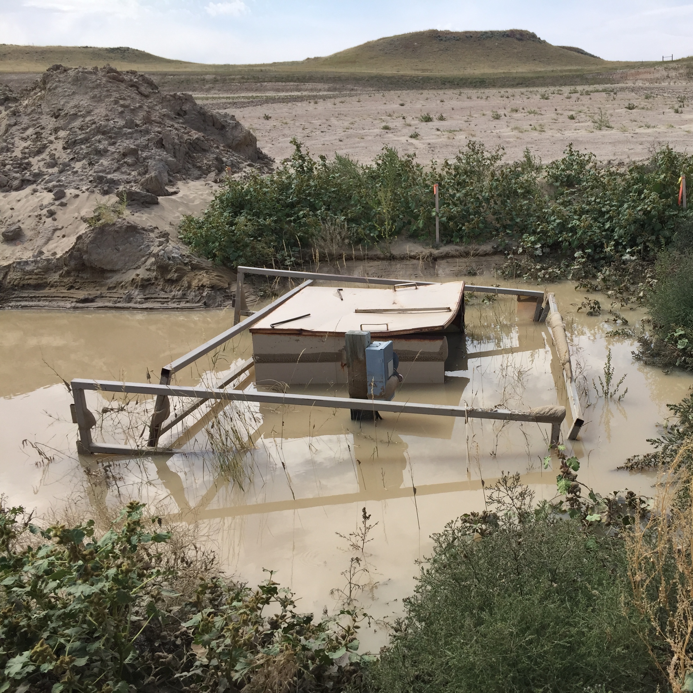 A coal-bed methane well sits abandoned in a pool of water outside Gillette, Wyo. It's more expensive than it looks to clean up.