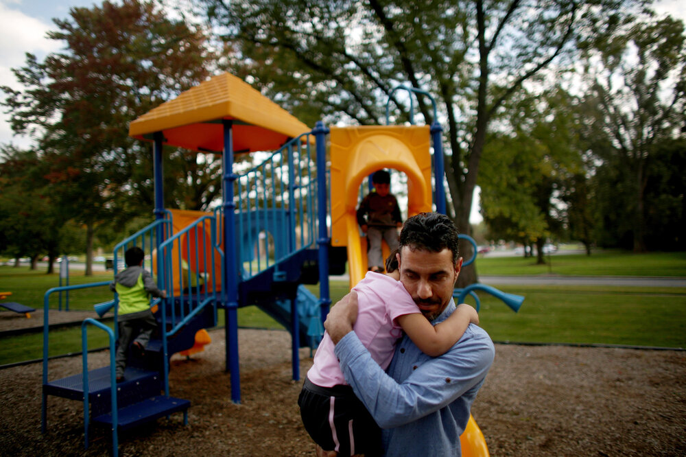 Omar holds his daughter, Taiba, at the playground near the family's new home in Toledo. (David Gilkey/NPR)