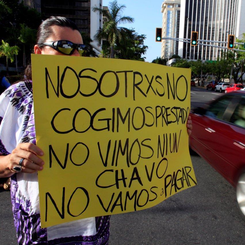 A demonstrator protesting the negotiations with Puerto Rico's creditors in July holds up a sign that reads,  "We didn't take out a loan. We didn't see a dime. We're not going to pay."