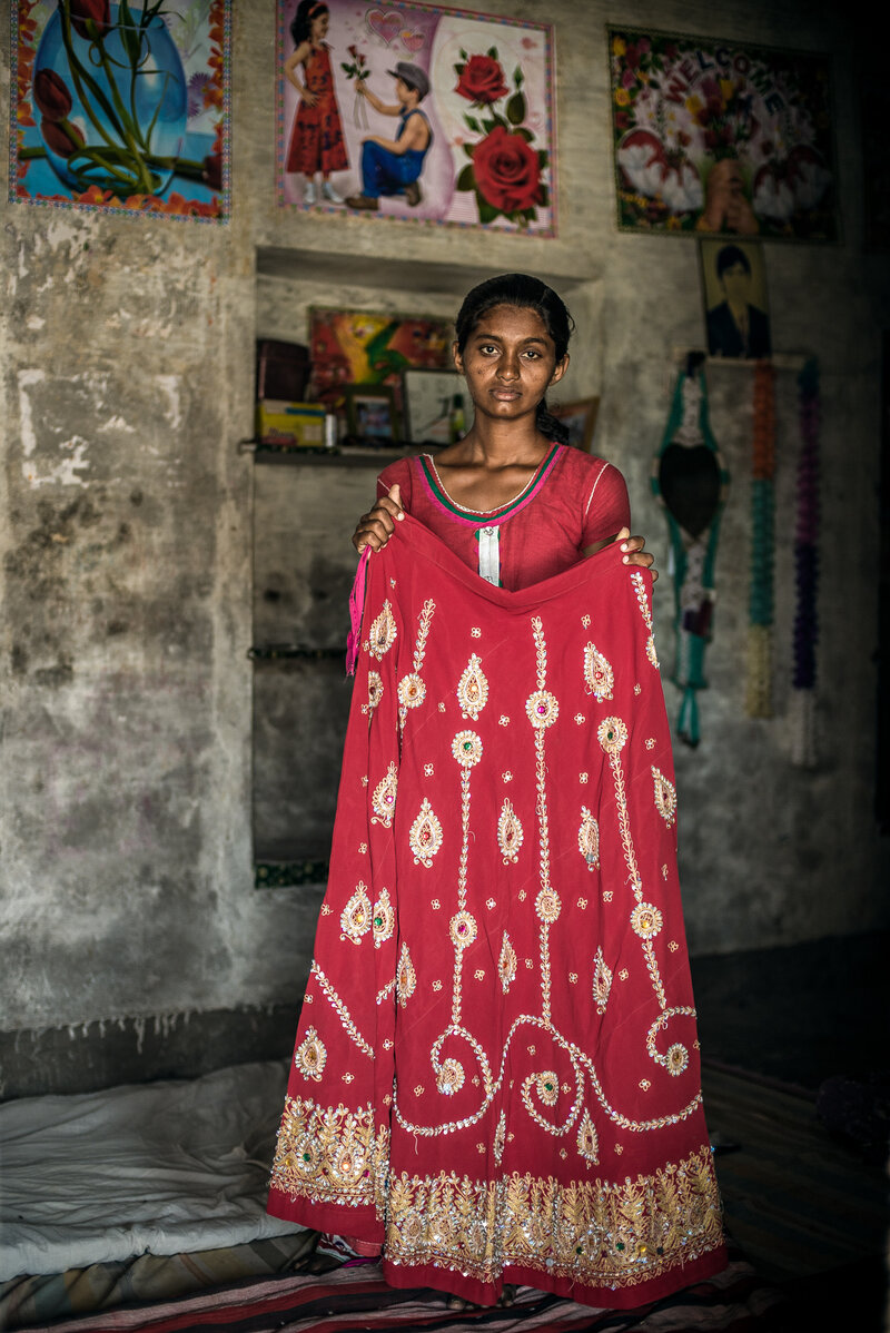 Nimmu's older sister, Durga, holds up part of the wedding dress that Nimmu was married in. It was too big for her, Nimmu says, and too old-fashioned. Nimmu's older sister, Durga, holds up part of the wedding dress that Nimmu was married in. It was too big for her, Nimmu says, and too old-fashioned.