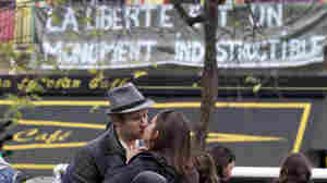 Two mourners kiss outside the Bataclan concert hall, one of the sites of Friday's terrorist attacks in Paris, now adorned with a banner reading "Freedom is an indestructible monument."