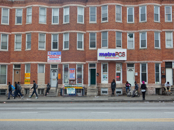 Pedestrians walk on West North Avenue in Baltimore. On Monday, the trial begins for the first of six police officers charged in Freddie Gray's death. (Jun Tsuboike/NPR)