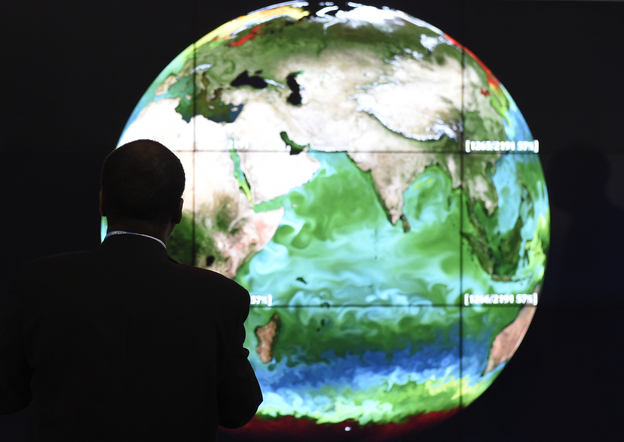 A conference attendee looks at a projection of the Earth on Monday, the opening day of the COP 21 United Nations conference on climate change, in Le Bourget, on the outskirts of Paris. (Image credit: AFP/Getty Images)