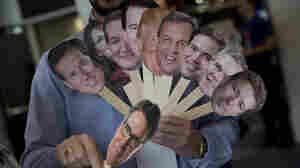 A reporter holds images of possible Republican candidates back in February. Since then, the GOP field has narrowed slightly, but still boasts 14 contenders.