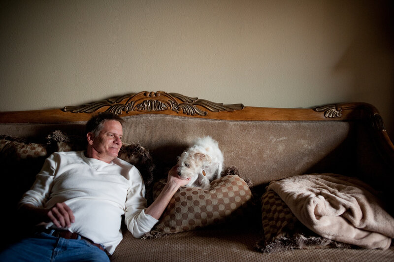 Schiller spends time with his Yorkie-doodle, Maxine, at his apartment. As a result of his mounting medical bills and his inability to work, he says he's now "next to poverty." (Brandon Thibodeaux for NPR) Schiller spends time with his Yorkie-doodle, Maxine, at his apartment. As a result of his mounting medical bills and his inability to work, he says he's now "next to poverty."
