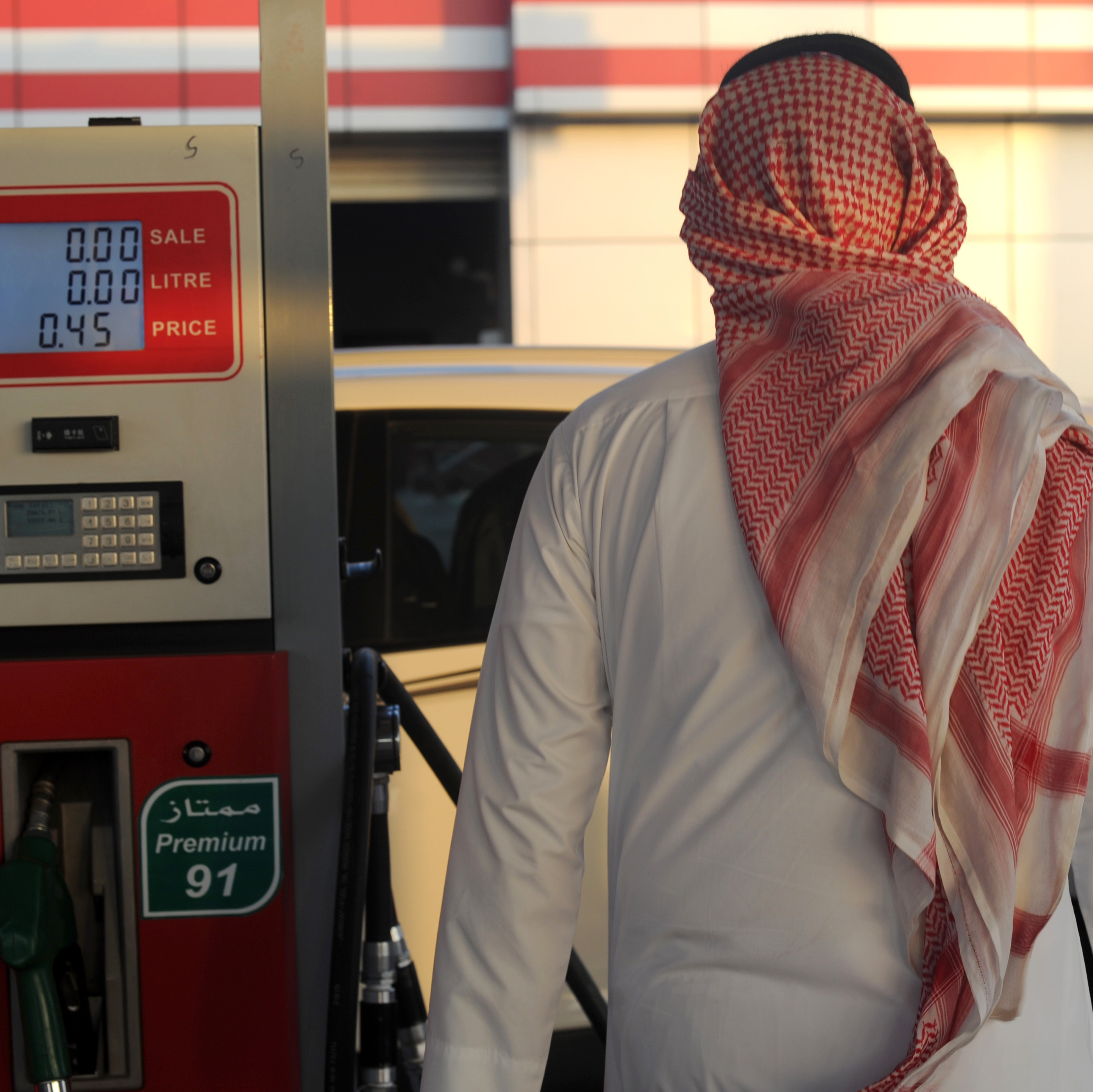 A Saudi man walks past a pump at a petrol station Monday in the Red Sea city of Jeddah. Saudi Arabia said it plans to reduce subsidies on power, water and fuel as part of new measures introduced in the face of low oil prices.