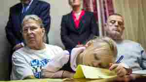 Flint, Mich., resident Jacqueline Pemberton holds her granddaughter at a press conference announcing a lawsuit against government officials in November. Pemberton is one of six plaintiffs claiming that officials violated constitutional rights by providing lead-tainted water to residents.