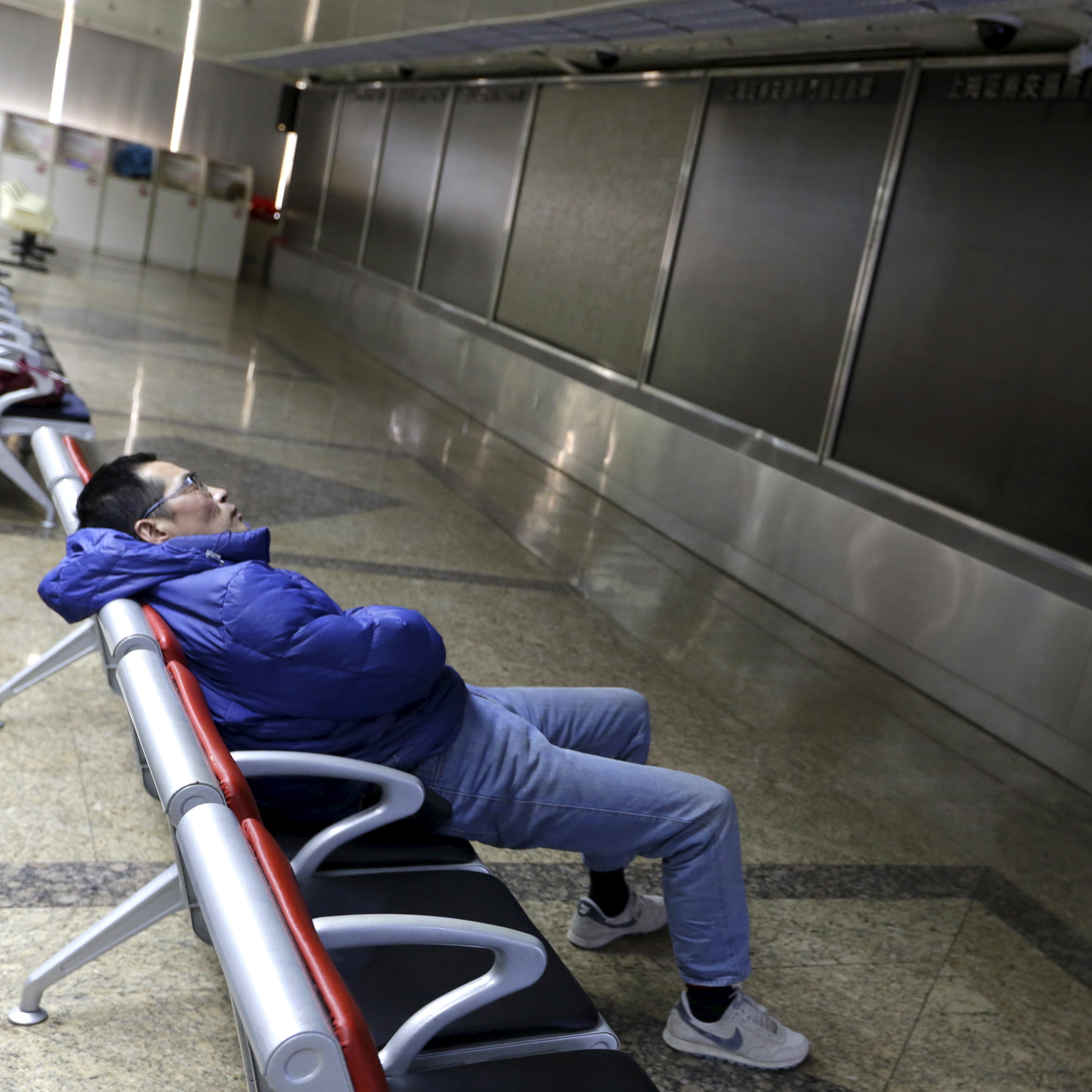 An investor rests in front of a dark electronic board at a Beijing brokerage house after China suspended trading Thursday for the second time this week.