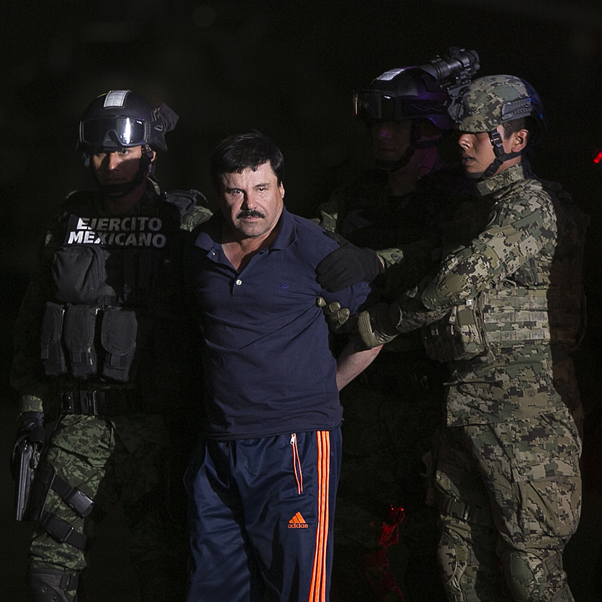 Joaquin 'El Chapo' Guzman, the world's most wanted-drug trafficker, second left, is escorted by Mexican security forces at a Navy hangar in Mexico City, Mexico, on Friday, Jan. 8, 2016.