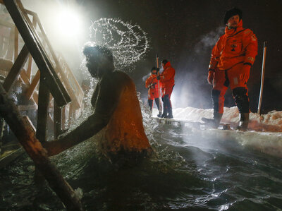 Rescue workers help Russian Orthodox believers marking Epiphany by swimming late Monday in a pond in Pushkin, outside St. Petersburg. Thousands of Russian Orthodox Church followers plunged into icy rivers and ponds across the country.