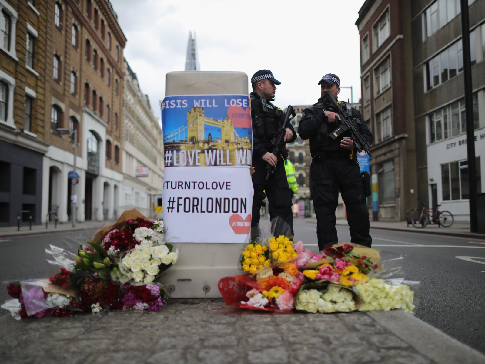 Police stand guard behind flowers left in memorial on Southwark Street near the scene of Saturday's terror attack in London. (Christopher Furlong/Getty Images)