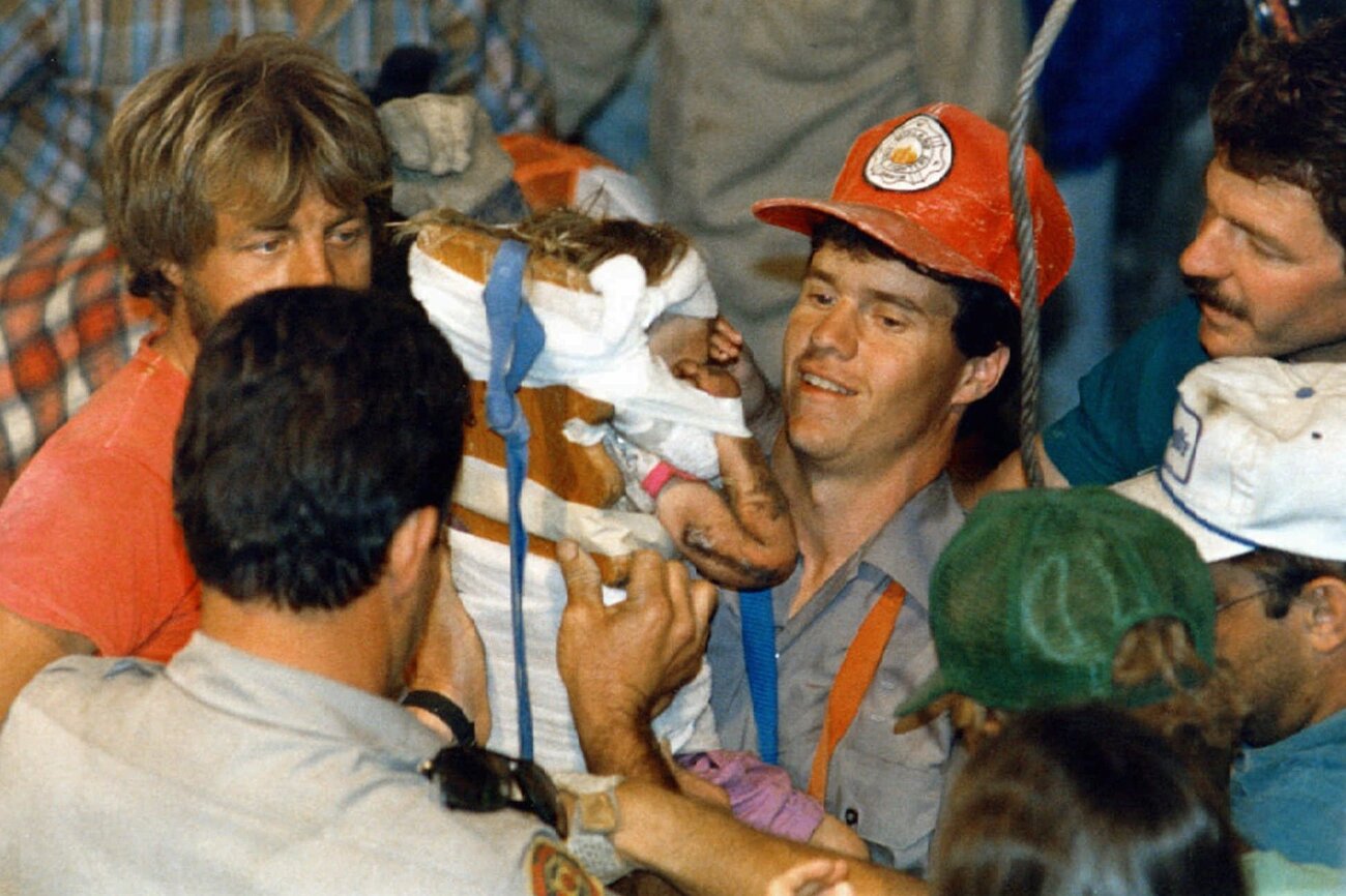 Rescue worker Steven Forbes carries 18-month-old Jessica McClure on Oct. 16, 1987, shortly after she was rescued from an abandoned water well in Midland, Texas. (Eric Gay/AP)