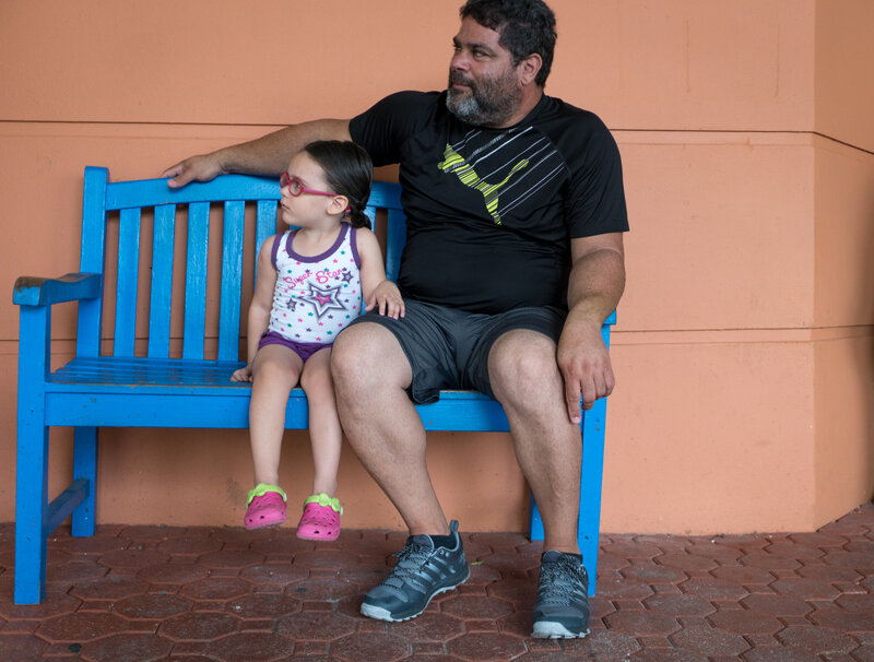 Angelica Alicea, 3, and her grandfather Julio Alicea wait outside the San Jorge Children's Hospital. (Angel Valentin for NPR)