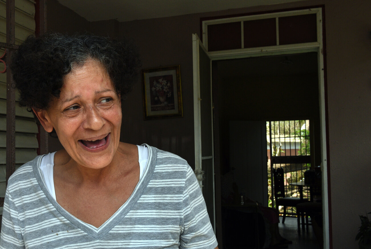 Daly Montavo, born in Puerto Rico and raised in New York City, laughs at her home on Avenida Esteves after filling jugs of water from a National Guard delivery to the neighborhood. She says, "We're here and that's all that matters." (Carol Guzy for NPR)