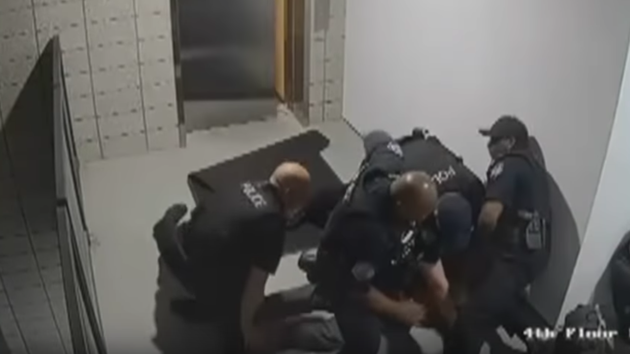 A still from surveillance footage, released by the police department in Mesa, Ariz., shows officers surrounding a man after they punched him to the ground.