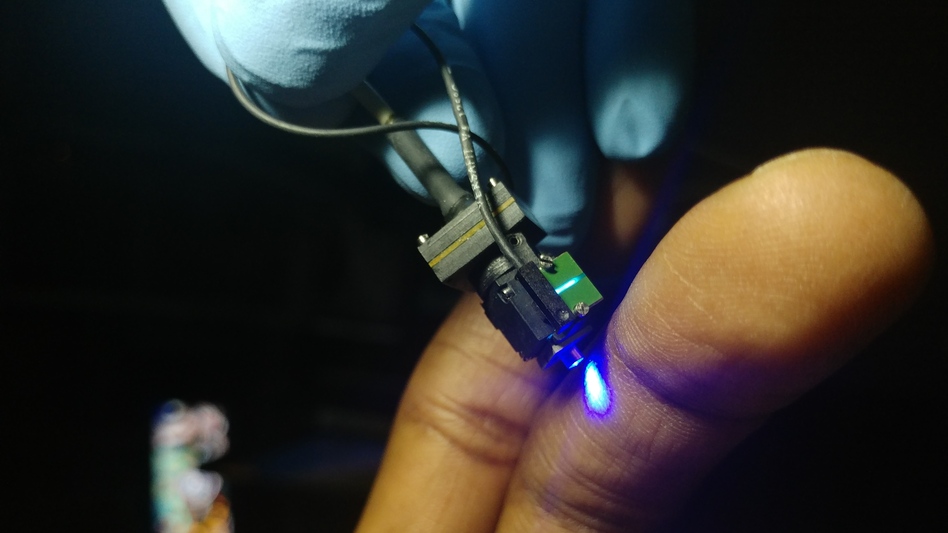 Biafra Ahanonu, a postdoctoral researcher at Stanford University, holds the miniature microscope he used to peer into the brains of mice.