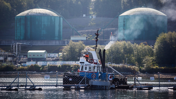 A tugboat operator secures a floating razor wire security fence during an emergency response exercise at the Kinder Morgan Inc. Westridge Marine Terminal in Burnaby, British Columbia, Canada, last September. A new expansion of the Trans Mountain pipeline would significantly expand tanker traffic in the region.