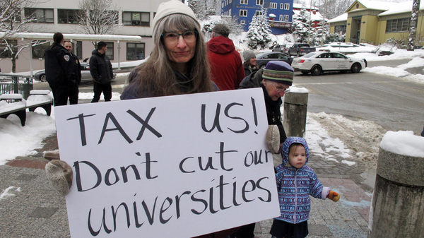 Luann McVey holds a sign before the start of a rally held in support of the Alaska university system on Feb. 13 in Juneau, Alaska.