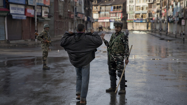 An Indian paramilitary soldier orders a man to lift his robe before frisking him in Srinagar on Thursday.