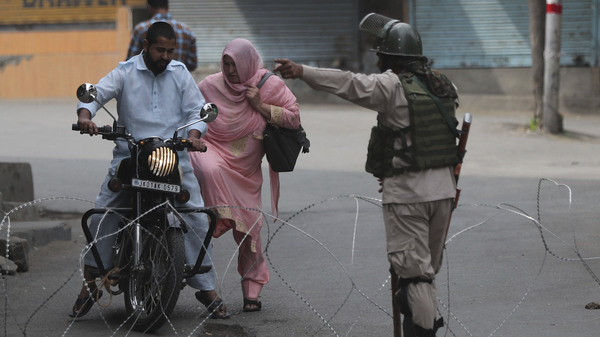 An Indian paramilitary soldier asks a Kashmiri couple on motorcycle to leave at a temporary checkpoint during restrictions in Srinagar, Indian-controlled Kashmir, on Friday.