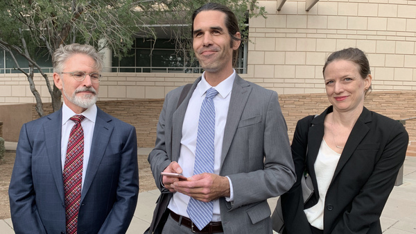 Scott Warren (center) of Ajo, Ariz., celebrates with his attorneys Amy Knight and Greg Kuykendall outside court in Tucson, Ariz. on Wednesday.
