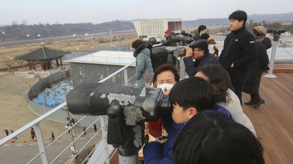 Visitors celebrating the New Year use binoculars to watch North Korean territory Wednesday, near the border between North and South Korea.