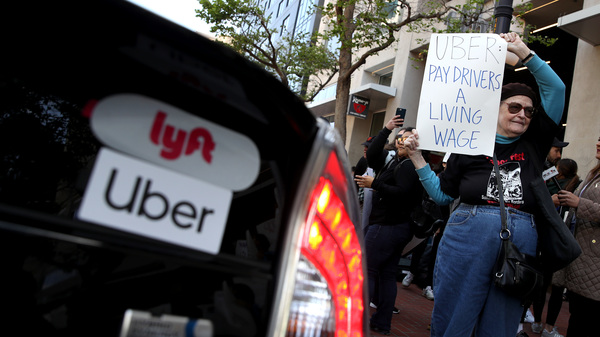 A supporter of ride-hail drivers from Uber and Lyft holds a sign during a protest in front of Uber headquarters on May 8, 2019 in San Francisco. A new law in California aims to change how gig economy, and other contract workers, are classified.