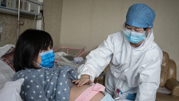 A nurse examines a pregnant woman in a private obstetric hospital in Wuhan, Hubei Province, China, in February. Research from China suggests pregnancy does make women more vulnerable to the coronavirus.