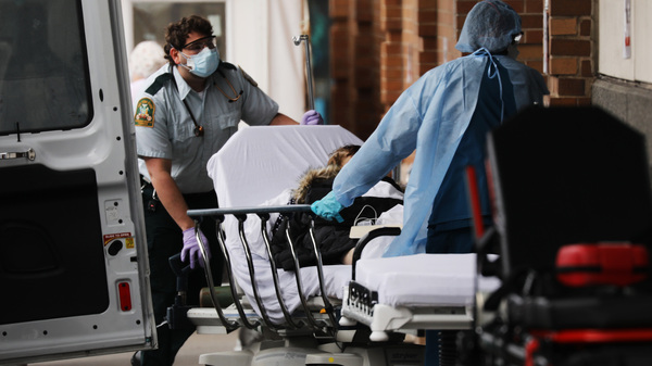 A patient with suspected COVID-19 arrives at Maimonides Medical Center in Brooklyn Thursday. Even as the risk of big medical bills climbs, many Americans are losing their jobs and health insurance right now.