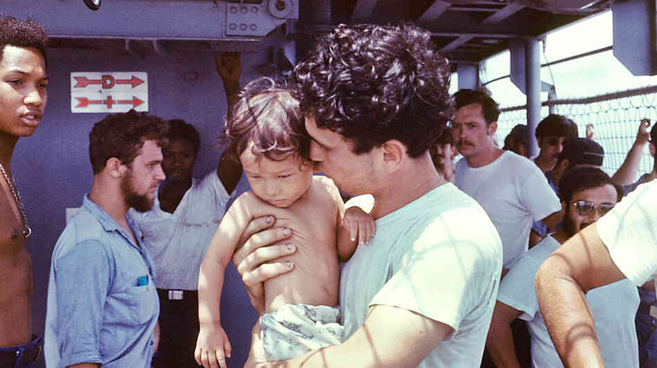 A USS Kirk crew member tends to a Vietnamese baby.