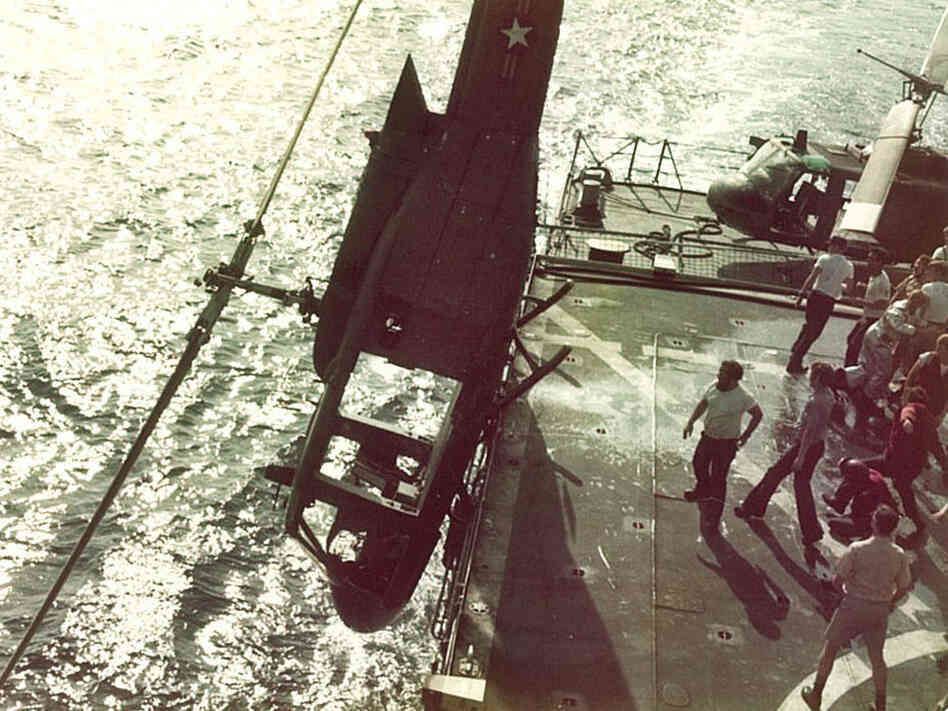 Crew members push a Huey into the ocean to make room for more helicopters full of refugees.