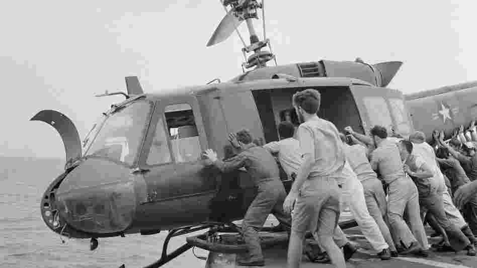 Crew members push a Huey into the ocean to make room for more helicopters full of refugees.