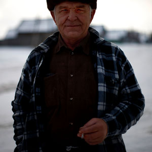 Yuri Bronnikov, a former engineer, stands in front of a wintry landscape on the shores of Lake Baikal. (David Gilkey/NPR)