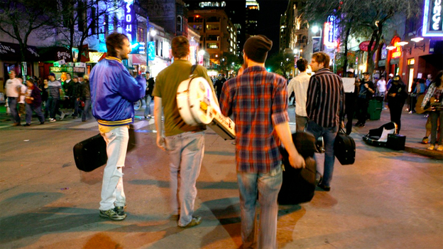 A band lugs their gear down 6th Street in Austin during SXSW.