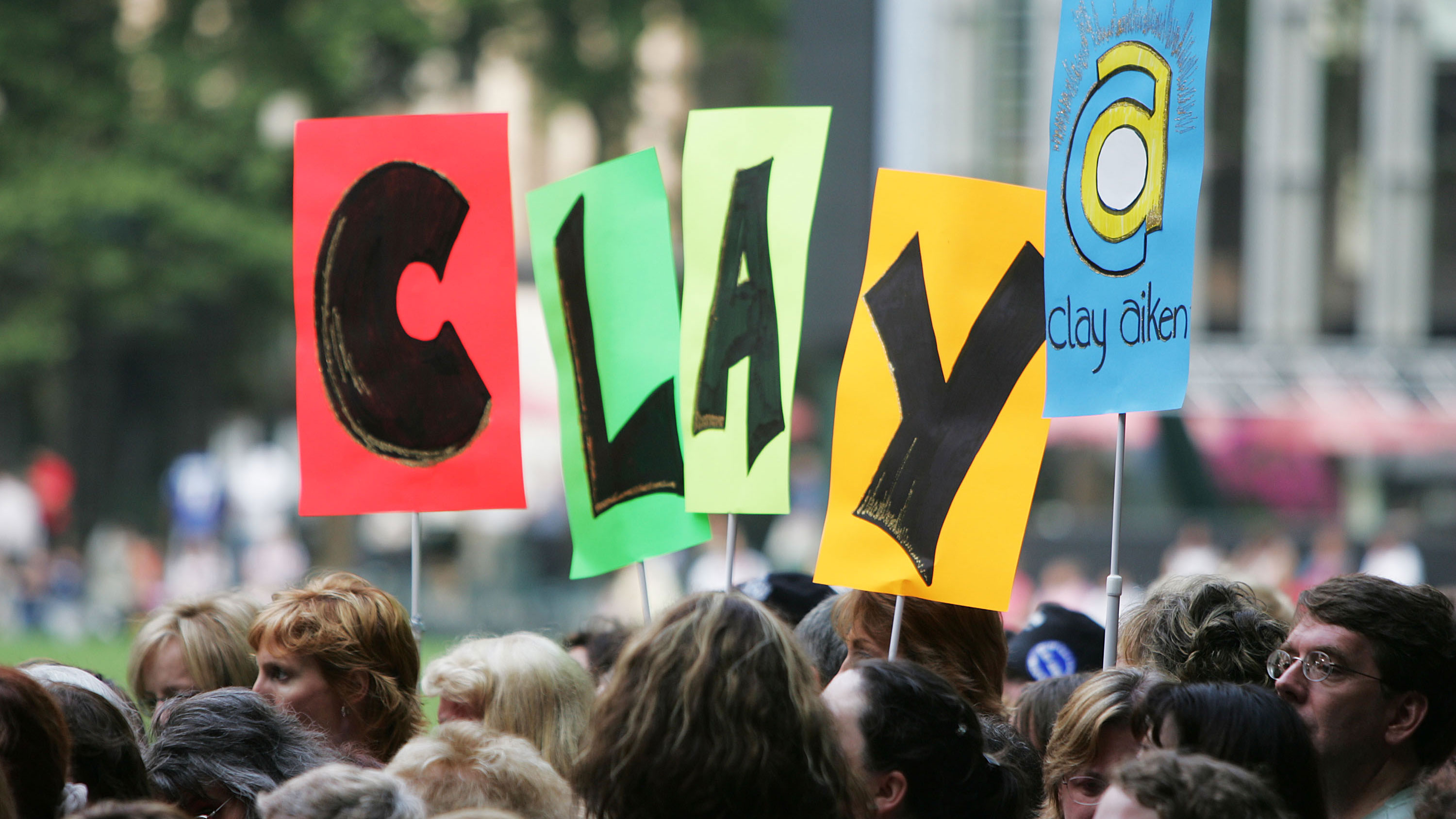 Fans hold up signs, loving Clay Aiken.