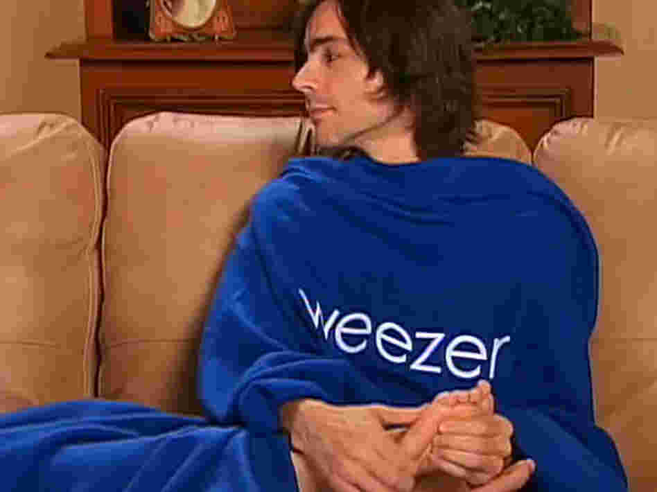 Weezer's Brian Bell rubs someone's feet in a Snuggie. Weezer's Brian Bell rubs someone's feet in a Snuggie.