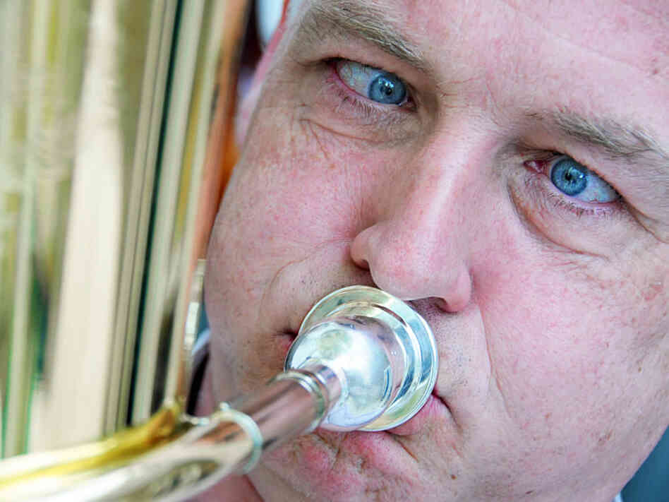 A man blows into a brass instrument