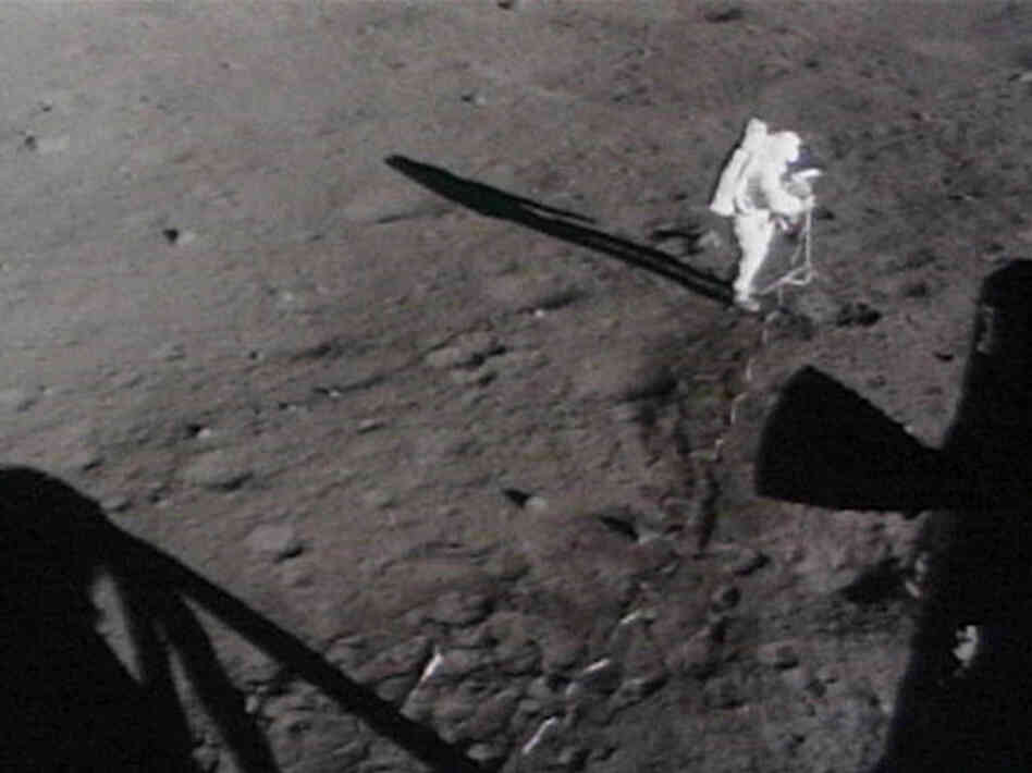 Astronauts move the lunar camera onto a tripod on the moon.