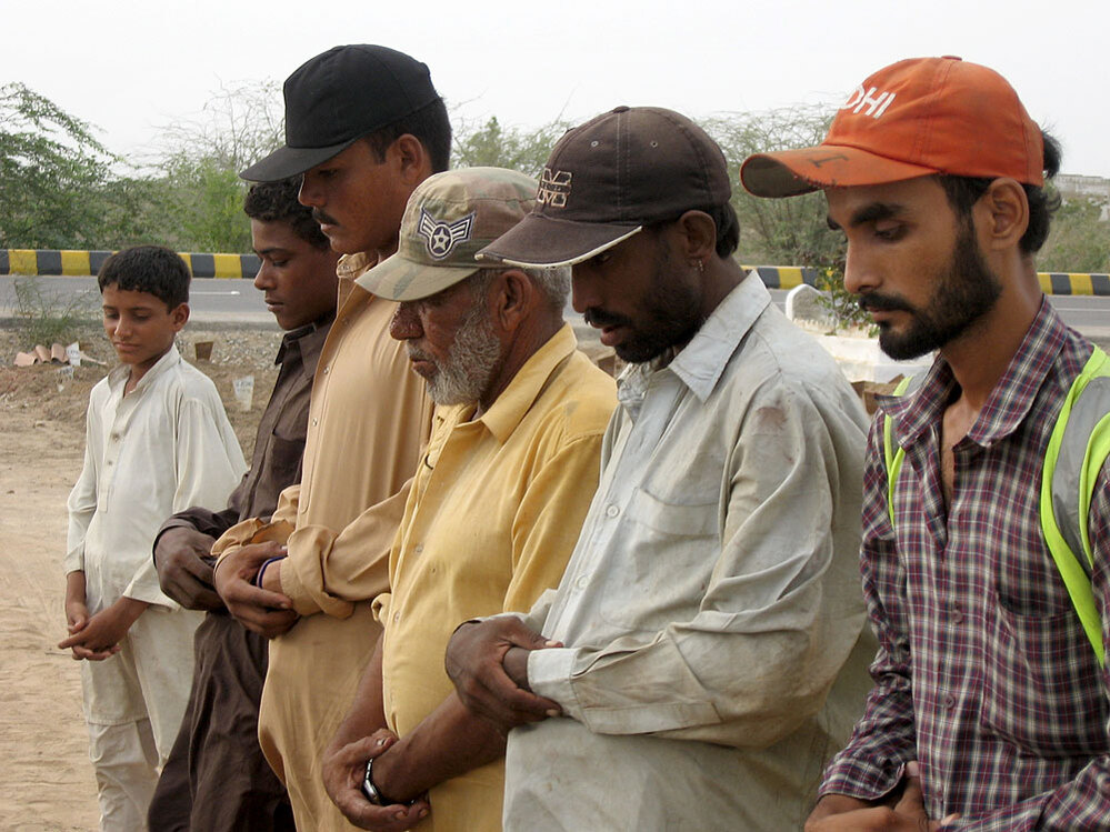 Gravediggers hold a short funeral service for a man found dead in the Karachi streets.