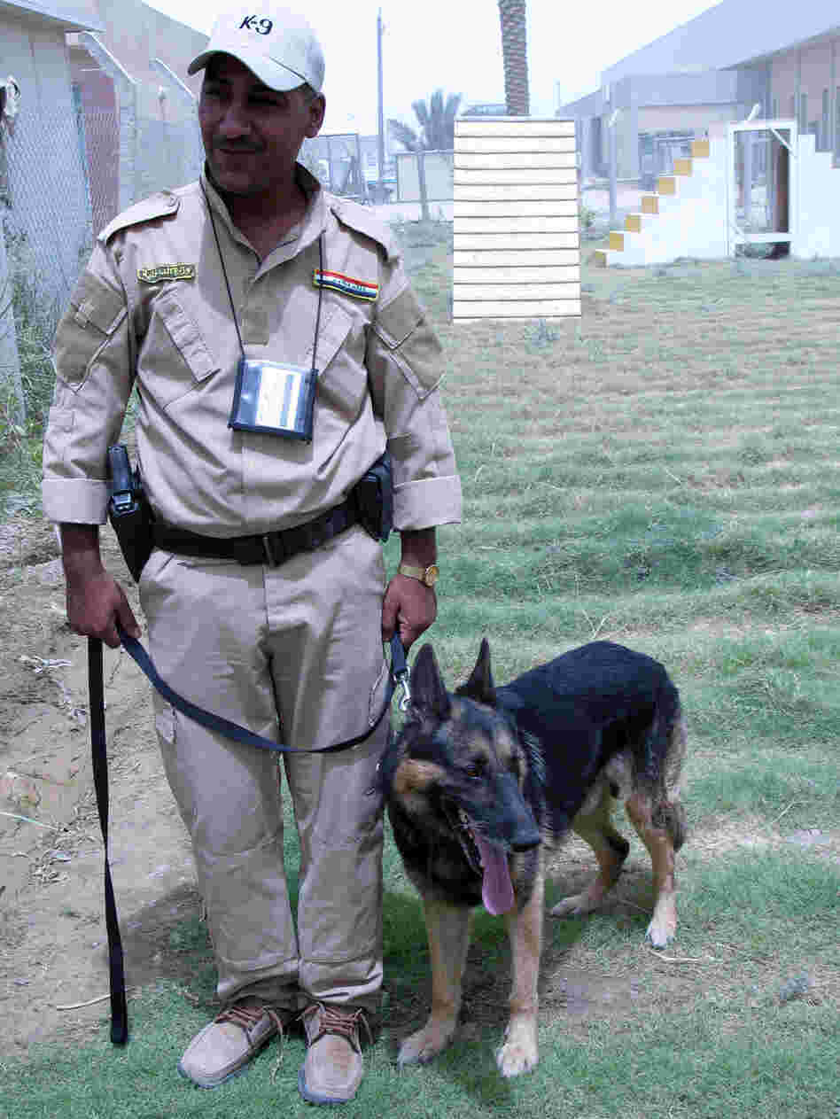 An Iraqi police officer in the Iraqi National Canine Program in Baghdad stands with his dog.
