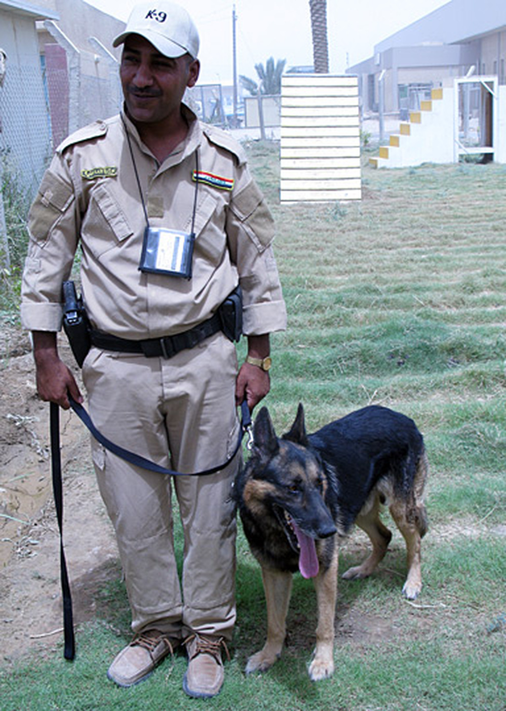 An Iraqi police officer in the Iraqi National Canine Program in Baghdad stands with his dog.