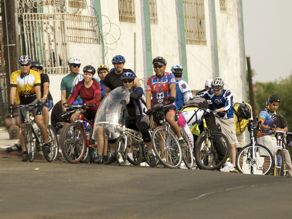 Tijuana bicyclists reach the top of a hill.