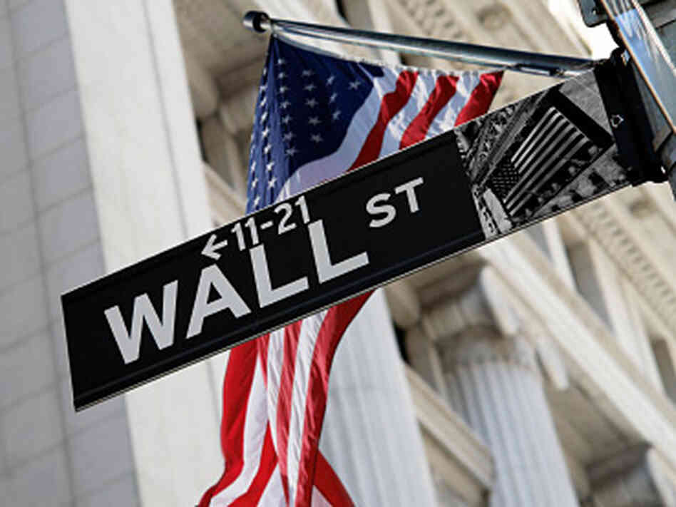U.S. flag behind Wall Street sign. U.S. flag behind Wall Street sign.