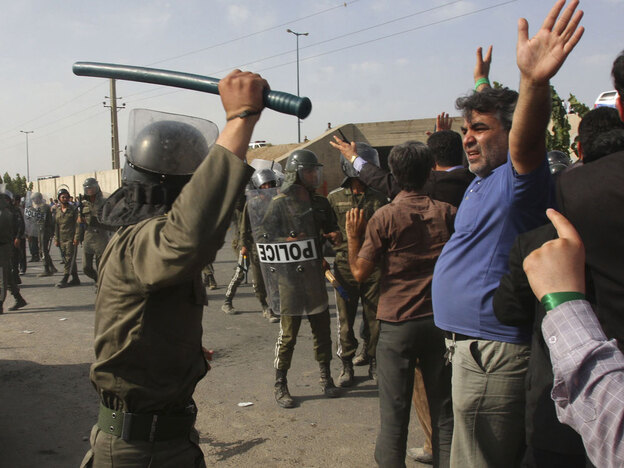 An Iranian policeman raises his baton to disperse protesters at an opposition rally in Tehran.