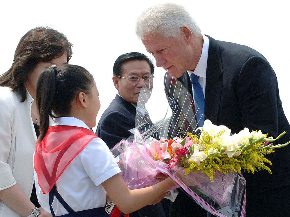 A young North Korean girl welcomes former President Bill Clinton with a bouquet of flowers.