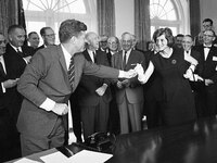 President John F. Kennedy hands a pen to his sister, Shriver, after using it to sign a $329 million mental health bill at a White House ceremony on Oct. 24, 1963.